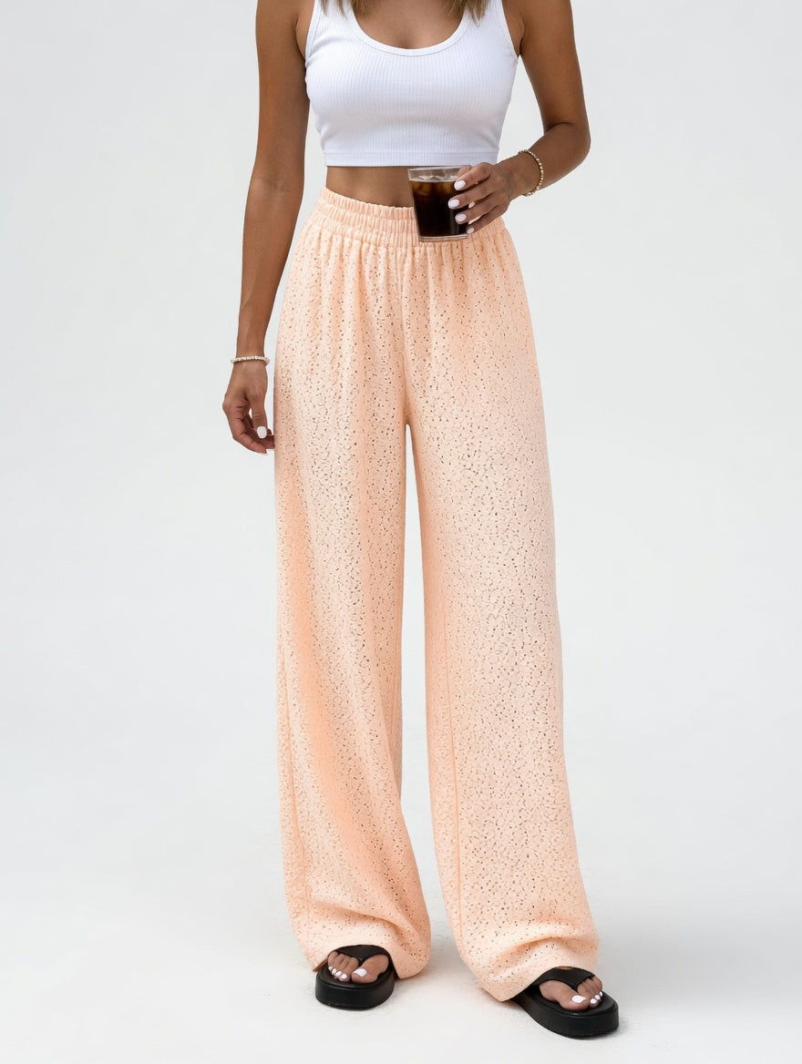 Person wearing peach textured pants and a white top on a white background